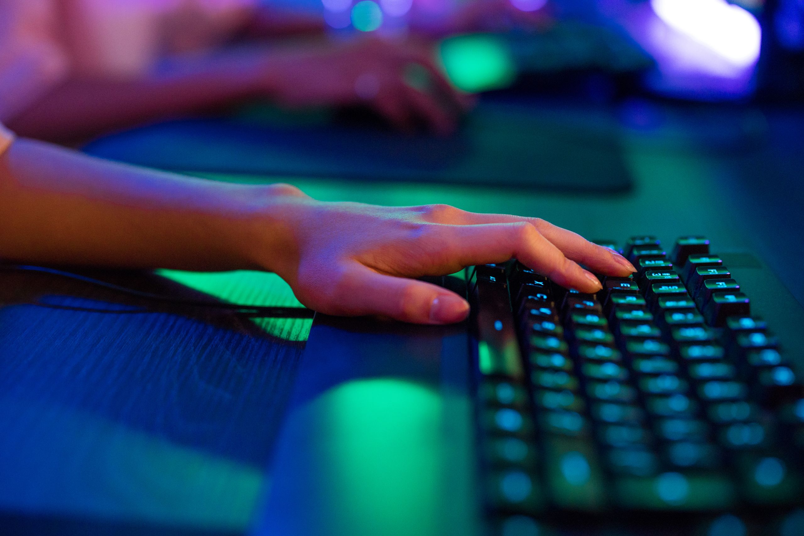A close-up image of a person's hand typing on a keyboard, illuminated by neon lights, creating a vibrant tech atmosphere.